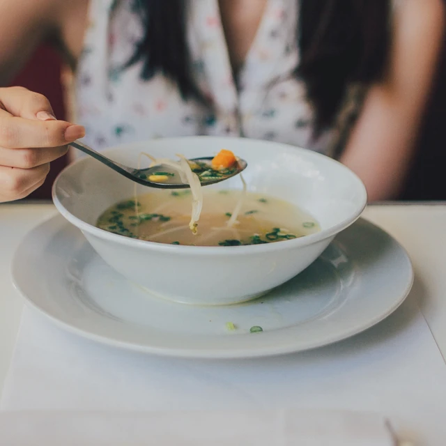 Woman eating noodle soup in a ceremic bowl