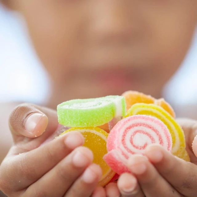 Cute asian child girl holding jelly candies in hand