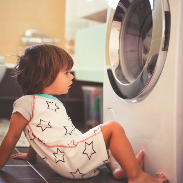 kid sitting in front of laundry machine