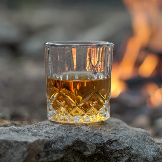 Glass of whiskey by campfire