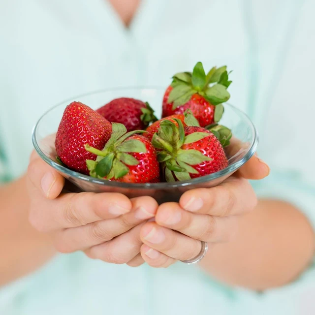 Woman holding strawberries in a glass bowl