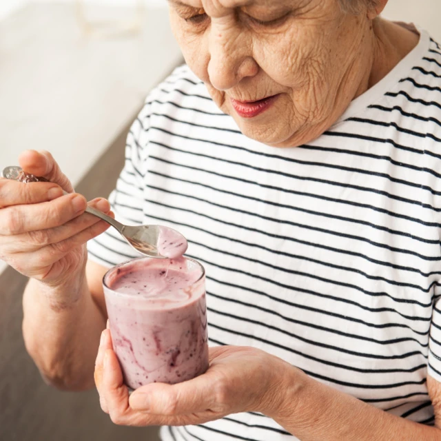 elder woman eating yogurt