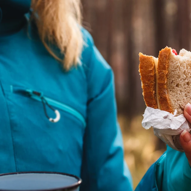 Woman in forest eating pulse bread sandwich