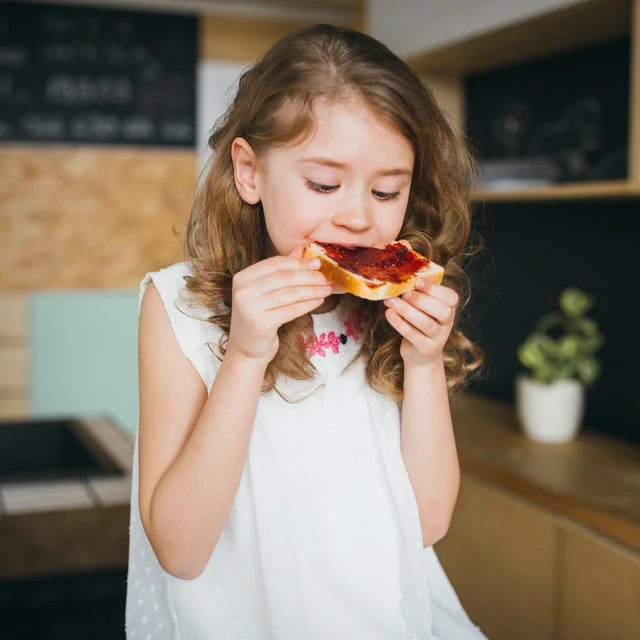 Young girl enjoying jam on bread