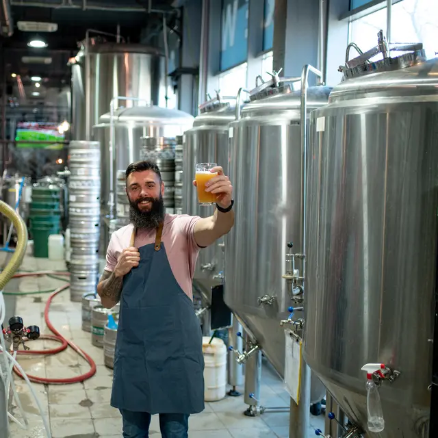 Brewmaster beside fermentation containers