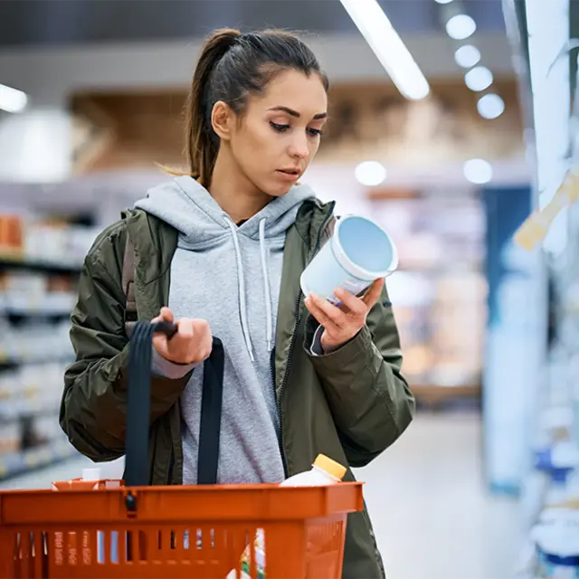 woman looking at label of plant-based yogurt alternative