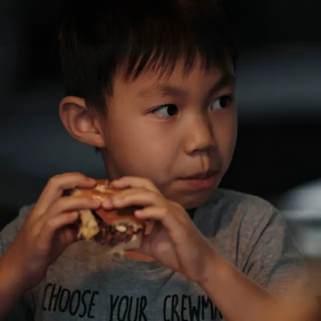 Boy eating climate-friendly burger made of plant-based meat