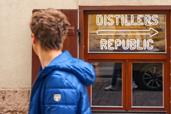 Man walking by distillery sign