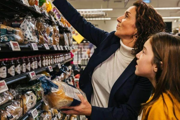 Mother and daughter buying bread in supermarket