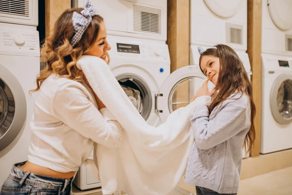 mother with daughter feeling freshly washed laundry