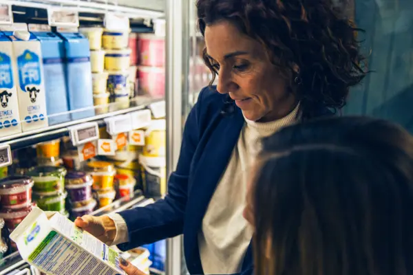 Consumer in supermarket checking the ingredient list of a plant-based drink product 