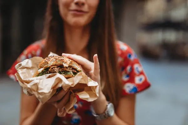 Woman enjoying the texture of a burger with plant-based meat