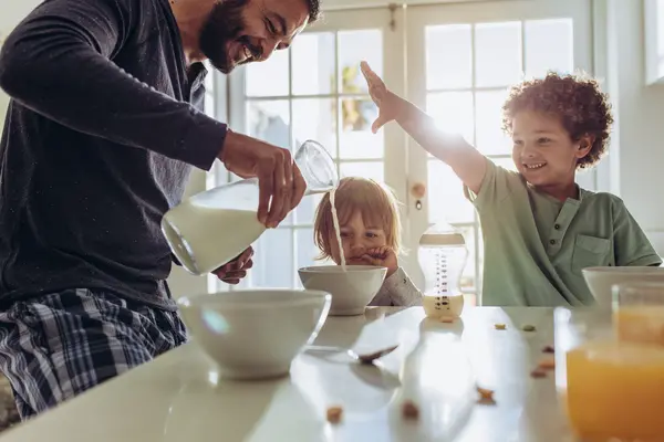 Happy_dad_pouring_oat_drink_to_his_two_kids
