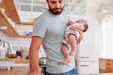 man cleaning while holding a baby