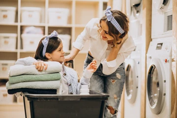 Girl doing laundry with her mother